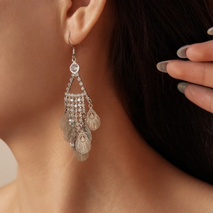 Close-up of silver tassel earrings with crystal hollow leaves on a model's ear