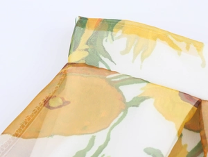 Macro shot of semi-transparent organza fabric featuring vibrant sunflower floral prints