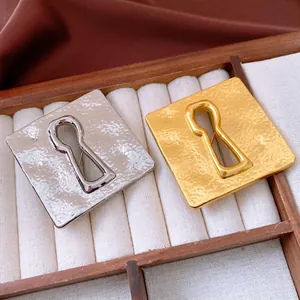 Vintage gold and silver wrinkled square keyhole brooches set in a wooden jewelry box