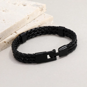 Detail of multi-layer braided black leather bracelet with magnetic metal clasp on stone