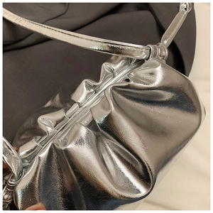 Detailed view of silver metallic pleated cloud bag featuring glossy texture and slim strap