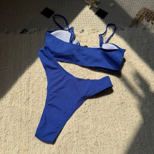 Detailed flat lay of blue ribbed bikini set with high cut bottoms on sand background
