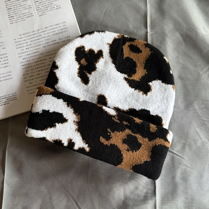 Detailed view of the cow print knit beanie showing black and white wool texture and pattern