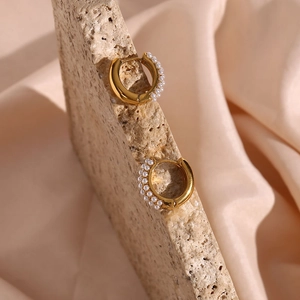 Detail shot of 18K gold plated hoop earrings with white pearls on a textured stone