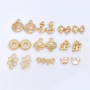 Collection of golden alloy charms including crown, anchor, and bow on white background