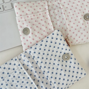 Close-up of fabric passport holder featuring polka dot patterns and metal magnetic clasp