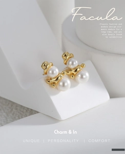 Macro detail of gold plated pearl snowman stud earrings on a geometric stand