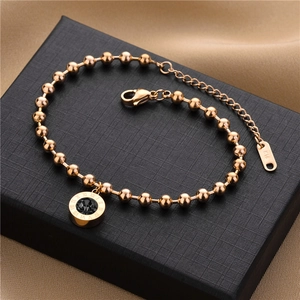 Macro shot of rose gold bead bracelet with Roman numerals and black stone on jewelry box