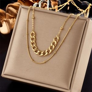 Detail of layered gold necklaces with fine bead and cuban chain in a luxury gift box