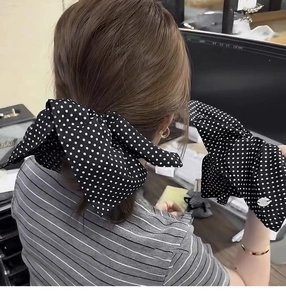 Detailed view of oversized black and white polka dot bow hair accessory and matching cuffs
