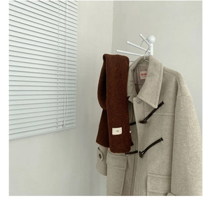 Close-up of dark brown knit wool scarf paired with a beige duffle coat with toggles