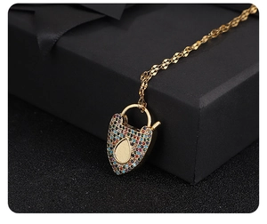 Detail of 18K gold plated lock pendant necklace with multicolor zircons on dark background
