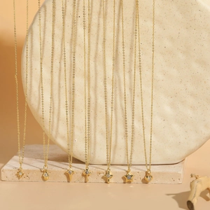 Detailed display of gold layered necklaces with star and heart zircon pendants on a stone base