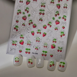 Close-up of 3D star and fruit nail stickers with silver foil edges on white nail tips