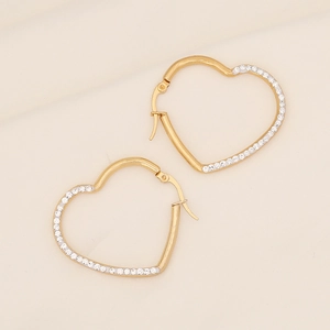 Polished gold heart hoop earrings with sparkling crystal pavé on textured beige fabric