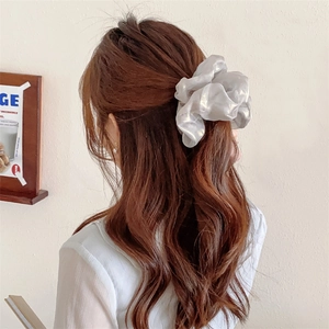 Elegant pearlescent silver silk scrunchie shown in a half-up ponytail hairstyle