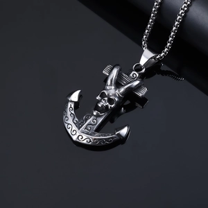 Macro shot of stainless steel anchor pendant with skull carving on a black reflective background