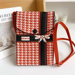 Detail of knitted houndstooth phone bag with bow decoration and adjustable shoulder strap