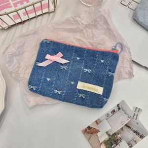 Close-up of denim coin purse with white polka dots and pink satin bow detail