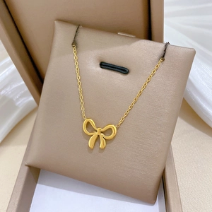 Close-up of golden bow necklace pendant on beige jewelry box cushion with soft lighting