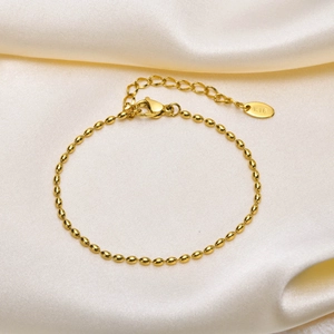 Detail of a gold rugby-style beaded bracelet with adjustable chain and K18 hallmark tag