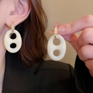 Détail de boucles d'oreilles géométriques blanc crème avec des accents dorés