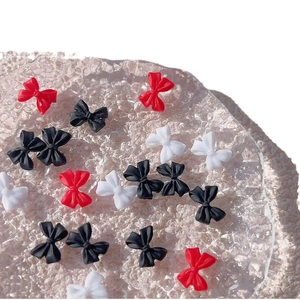 Matte resin bow nail art charms in black, red, and white on bubble display base