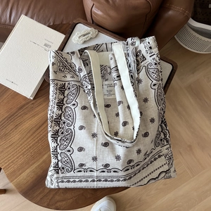 Detailed view of paisley canvas tote bag with woven straps on a rustic wooden table