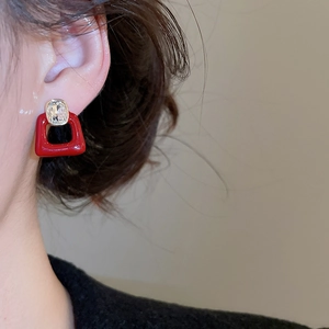 Close-up of a red zircon square stud earring with clear crystal and gold plating