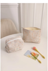 Detailed view of tweed cosmetic bags with woven texture and gold-handle makeup brushes