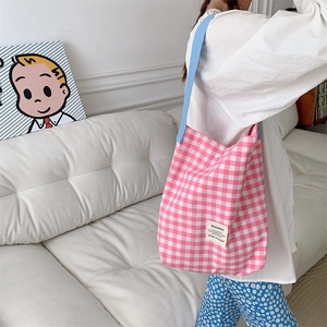 Détail du sac cabas en toile à carreaux roses avec anses bleues et étiquette blanche