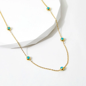Golden stainless steel necklace with blue evil eye beads on white geometric stone