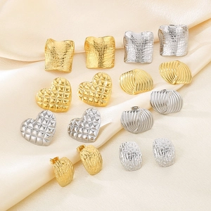 Detailed close-up of mixed heart and geometric stainless steel earrings on silk