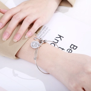 Polished stainless steel adjustable bangle with star and moon charms worn on a wrist