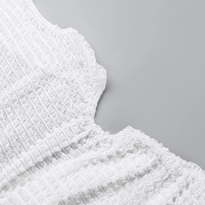 Detailed close-up showing the intricate texture and elastic pleats of the white dress