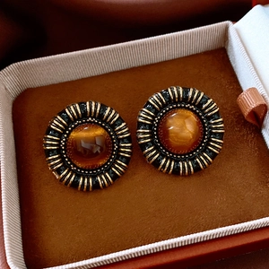 Macro shot of vintage round resin earrings with amber center and ornate gold-tone frame