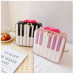 Detail of sweet piano key bags with bows, shown in black-white and iridescent pink