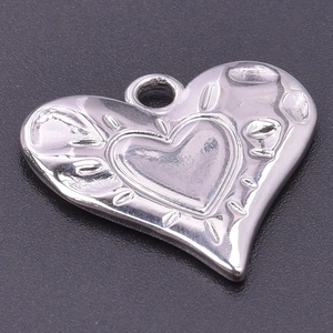 Detail shot of heart-shaped silver pendant with embossed double heart pattern and loop