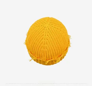 Vue de dessus d'un bonnet en maille jaune vif vieilli avec détails de bords effilochés