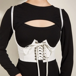 Détail d'une ceinture corset en similicuir blanc avec œillets métalliques et lacets