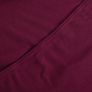 Gros plan du tissu tricoté bordeaux montrant la texture fine et les doubles coutures