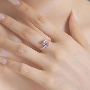 Detail of S925 silver ring featuring dual pink heart-shaped zircons on female hand
