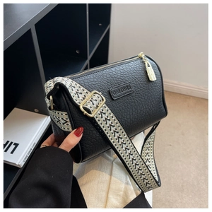 Detail der schwarzen Zylindertasche aus Leder mit gewebtem Gurt und goldenem Zipper