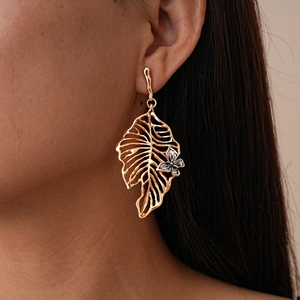 Metallic gold leaf earring with silver butterfly detail worn by model in close-up shot
