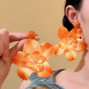 Vista detallada de estos pendientes de flores de rafia naranja hechos a mano para el verano