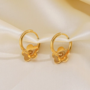 Boucles d'oreilles fleurs en acier doré 18K sur fond de tissu en soie beige