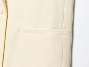 Détail macro du tissu beige texturé avec une couture de poche et bouton assorti
