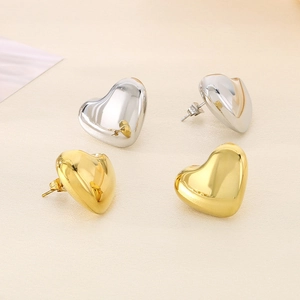 Minimalist heart stud earring set in polished gold and silver finishes on textured background