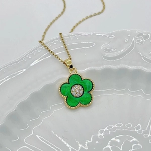 Detail of green five-petal flower pendant with gold beads and a central diamond accent