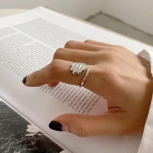 Detail of 925 sterling silver ring with shell texture on a model hand with book background